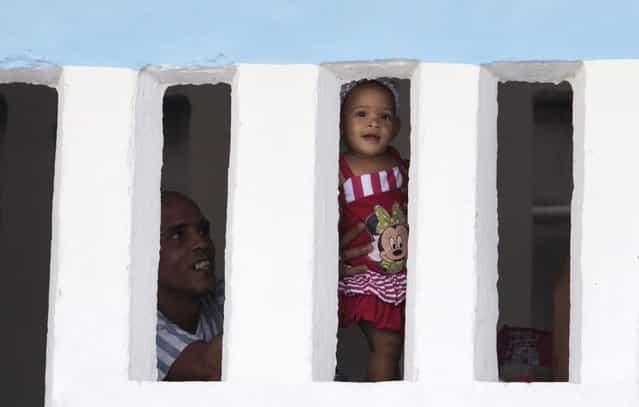 A prisoner holds up a young visitor toward the press during visiting hours a the Combinado del Este prison during a media tour of the prison in Havana, Cuba, Tuesday, April 9, 2013. Cuban authorities led foreign journalists through the maximum security prison, the largest in the Caribbean country that houses 3,000 prisoners. Cuba says they have 200 prisons across the country, including five that are maximum security. (Photo by Franklin Reyes/AP Photo)