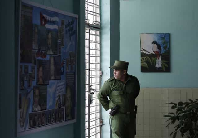 A military guard looks through the window from inside the medical clinic at the Combinado del Este prison during a media tour in Havana, Cuba, Tuesday, April 9, 2013. Cuban authorities led foreign journalists through the maximum security Eastern Combined, the largest prison in the Caribbean country that houses 3,000 prisoners. Cuba says they have 200 prisons across the country, including five that are maximum security. (Photo by Franklin Reyes/AP Photo)