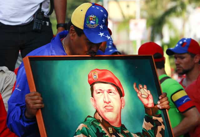 Venezuela's acting President and presidential candidate Nicolas Maduro kisses a painting of late Venezuelan president Hugo Chavez during a campaign rally in the state of Vargas April 9, 2013. Venezuelans will hold presidential elections on April 14. Maduro promised on Tuesday to hike Venezuela's minimum wage by about 40 percent if he is elected in a weekend vote to replace late socialist leader Chavez. (Photo by Carlos Garcia Rawlins/Reuters)