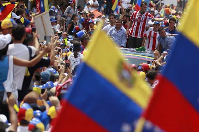 Venezuela's opposition leader and presidential candidate Henrique Capriles (R) greets supporters during a campaign rally in the state of Merida April 10, 2013. Capriles denied on Wednesday accusations from acting President Nicolas Maduro that he would scrap popular welfare policies if he wins Sunday's election. (Photo by Carlos Garcia Rawlins/Reuters)