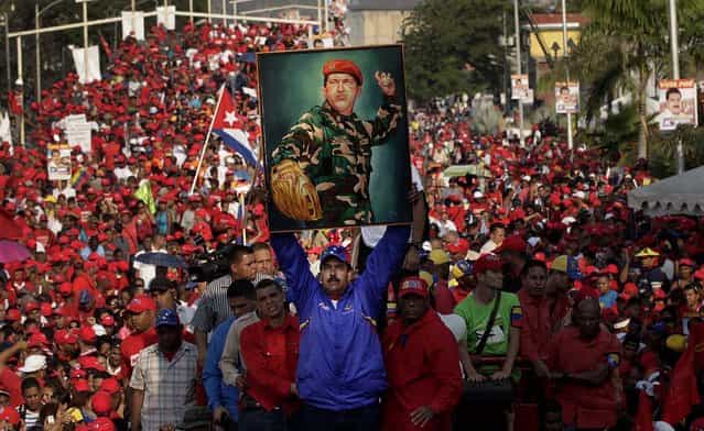 Venezuela's acting President Nicolas Maduro holds up a painting of Hugo Chavez during a campaign rally in Catia La Mar, on April 9, 2013. Maduro, the hand-picked successor of Chavez, is running for president against opposition candidate Henrique Capriles on April 14. (Photo by Ariana Cubillos/Associated Press)