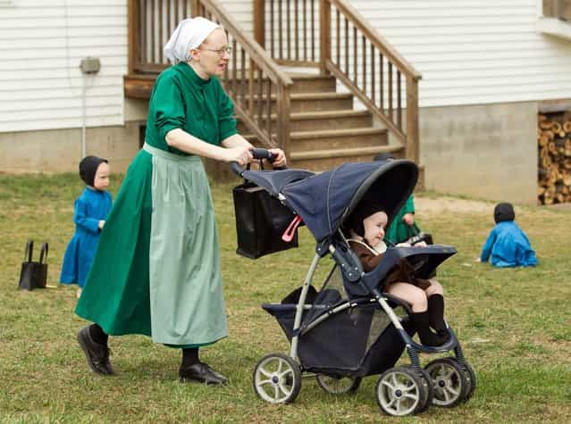 Emma Miller pushes her son in a stroller outside the schoolhouse in Bergholz, Ohio, Tuesday, April 9, 2013. Miller, along with three other women and a man from this tight-knit community in rural eastern Ohio, will enter prison on Friday, April 12, joining nine already behind bars on hate crimes convictions for hair- and beard-cutting attacks against fellow Amish. (Photo by Scott R. Galvin/AP Photo)