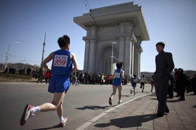 People watch marathon runners near the Arch of Triumph in Pyongyang, North Korea, Sunday, April 14, 2013. North Koreans held the 26th Mangyongdae Prize Marathon to mark the upcoming birthday of the late leader Kim Il Sung on April 15. (Photo by Alexander F. Yuan/AP Photo)