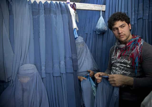 In this Thursday, April 11, 2013 photo, Nazar, right, a salesman at a burqa store, helps women to choose a burqa at a shop in the old town of Kabul, Afghanistan. (Photo by Anja Niedringhaus/AP Photo)