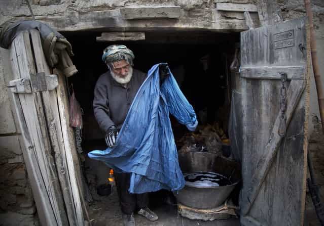Haji Hussain, 75, who colors clothing for 40 years, takes a freshly colored burqa out for drying in his small shop in the old town of Kabul, Afghanistan, Monday, April 15, 2013. (Photo by Anja Niedringhaus/AP Photo)