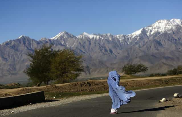 An Afghan woman in a burqa walks along a road on a windy day on the outskirts of Kabul April 16, 2013. (Photo by Mohammad Ismail/Reuters)