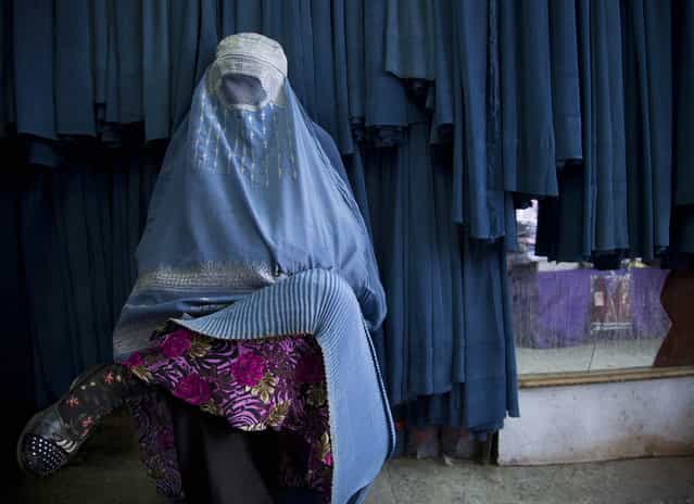 In this Thursday, April 11, 2013 photo, an Afghan woman waits to get in line to try on a new burqa at a shop in the old town of Kabul, Afghanistan. (Photo by Anja Niedringhaus/AP Photo)