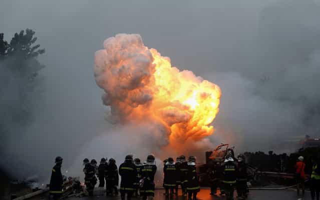 Firefighters work to put out a fire as white phosphorus exploded after a violent collision when a truck crashed into another vehicle on a highway in Wuhan, central China's Hubei province on April 19, 2013. One of the two truck drivers was killed in the accident while the other succeeded to get out of the truck before the explosion. (Photo by AFP Photo)