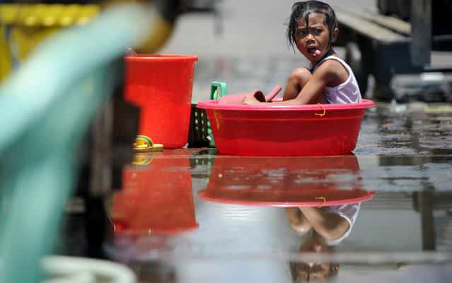 A girl cools off in a water basin in Manila on April 19, 2013. The Philippines has been experiencing the hottest days of the year with temperatures of 35 degrees Celsius (95 Fahrenheit) recorded in parts of the city. (Photo by Noel Celis/AFP Photo)