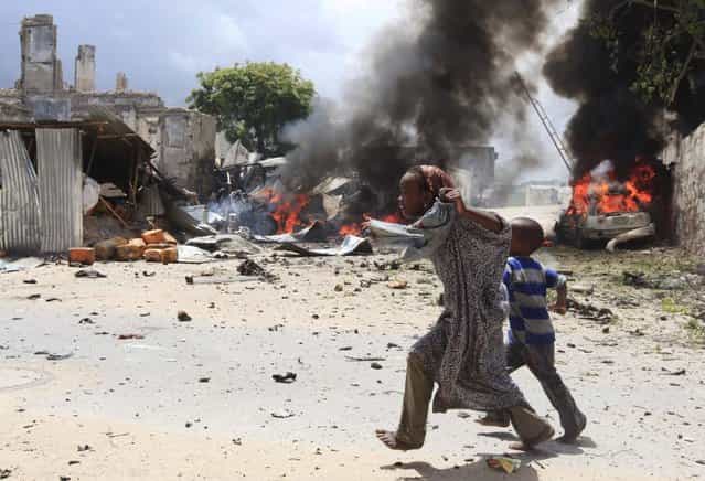 A Somali girl and her brother run to safety near the scene of a blast in Mogadishu April 14, 2013. At least 16 people were killed as two car bombs exploded outside the law courts in Somalia's capital Mogadishu and gunmen stormed the building on Sunday, before a gunbattle erupted with security forces besieging the compound, witnesses said. (Photo by Feisal Omar/Reuters)