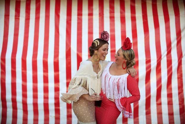 Women wearing typical Sevillana outfits laugh during the traditional Feria de Abril (April fair) in the Andalusian capital of Seville, southern Spain April 18, 2013. The fair will run until April 21. (Photo by Marcelo del Pozo/Reuters)