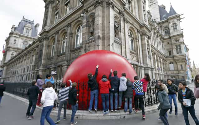 Children play with a huge red ball which is installed outside the Hotel de Ville City Hall as part of the RedBall Project by artist Kurt Perschke in Paris April 19, 2013. The RedBall Project is touring Paris from April 18 to 28, 2013, changing its location each day. (Photo by Charles Platiau/Reuters)