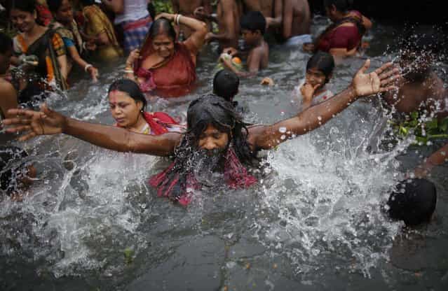 A devotee takes a holy bath as he offers prayers to the rising sun during the [Astami Snan] festival in the Brahmaputra river at Langalbandh, 20km (12.5 miles) from the capital Dhaka April 18, 2013. Hindus in Bangladesh are celebrating [Astami Snan], a festival involving a holy bath ritual in the river, which they believe will wash away their sins. (Photo by Andrew Biraj/Reuters)