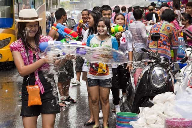 A woman reacts to being soaked by water during a community water fight as part of the Songkran water festival on April 14, 2013 in Bangkok, Thailand. The Songkran festival marks the traditional Thai New Year and is celebrated each year from April 13 to 15. The throwing of water originated as a way to pay respect to people and is meant as a symbol of cleansing and purification. (Photo by Jack Kurtz)
