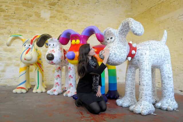 Lauren Vincent, fundraising manager for Gromit Unleashed, poses on April 19, 2013 with four, of around 70, Gromit sculptures painted by (left to right) Sir Paul Smith, Cath Kidston, Richard Williams and Simon Tofield, at a secret location in Bristol before they are placed for public view on an arts trail around the city from July 1st. After the public arts trail the sculptures will be auctioned to raise funds for Wallace and Gromit's Grand Appeal's campaign to raise funds for the expansion of Bristol Children's Hospital. (Photo by Tim Ireland/PA Wire)