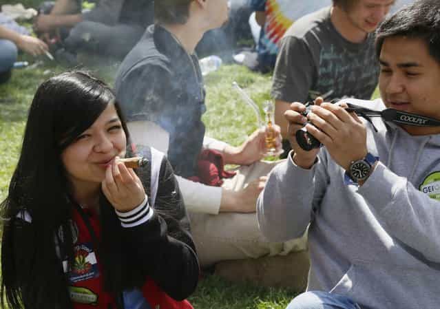 A woman smokes a blunt as a friend takes her picture at the 4/20 marijuana holiday in Civic Center Park in downtown Denver April 20, 2013. (Photo by Rick Wilking/Reuters)