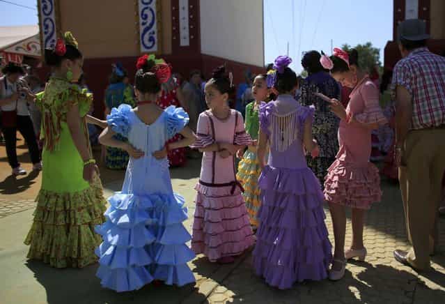 Girls wearing traditional Sevillana outfits wait during the traditional Feria de Abril (April fair) in the Andalusian capital of Seville April 16, 2013. (Photo by Marcelo del Pozo/Reuters)