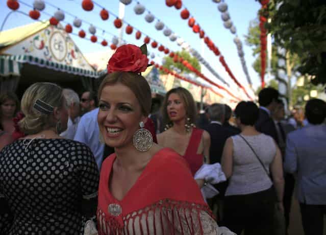 A woman wearing a typical Sevillana outfit smiles during the traditional Feria de Abril (April fair) in the Andalusian capital of Seville, southern Spain April 18, 2013. (Photo by Marcelo del Pozo/Reuters)