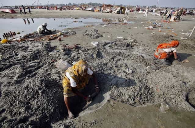 Indian women search for coins offered by devotees near the polluted waters of Ganges River at Sangam, the confluence of the Ganges, Yamuna, and the mythical Saraswati River, in Allahabad, India, Monday, April 22, 2013. April 22 is observed as Earth Day every year as a tool to raise ecological awareness. (Photo by Rajesh Kumar Singh/AP Photo)