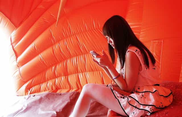 A woman sits inside an inflatable sculpture of a pig called ['House of Treasures] by Chinese contemporary artist Cao Fei on display as part of the [Inflation!] exhibition curated by Mobile M + on April 24, 2013 in Hong Kong. The inflatable artwork is one of six on display as part of the exhibition which is open from April 25, 2013 until June 9, 2013. (Photo by Jessica Hromas)