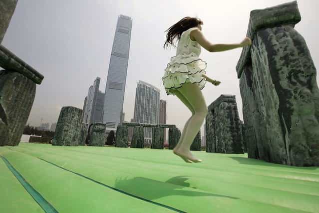 A member of the public bounces on a life-size interactive inflatable sculpture of Stonehenge called [Sacrilege 2012] by English contemporary artist Jeremy Deller on display as part of the [Inflation!] exhibition curated by Mobile M + on April 24, 2013 in Hong Kong. The inflatable artwork is one of six on display as part of the exhibition which is open from April 25, 2013 until June 9, 2013. (Photo by Jessica Hromas)