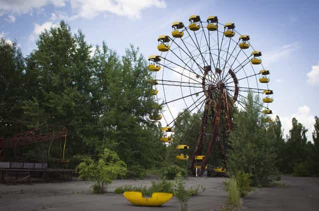 This June 8, 2011 photo shows a Ferris wheel at a playground in the deserted town of Pripyat, Ukraine, some 3 kilometers (1.86 miles) from the Chernobyl nuclear plant. Chernobyl and Fukushima are some 5,000 miles apart but have much in common. The towns nearest to each of these stricken nuclear power stations, in Ukraine and Japan, whose disasters struck 25 years apart, already reveal eerie similarities. (Photo by Sergey Ponomarev/AP Photo)