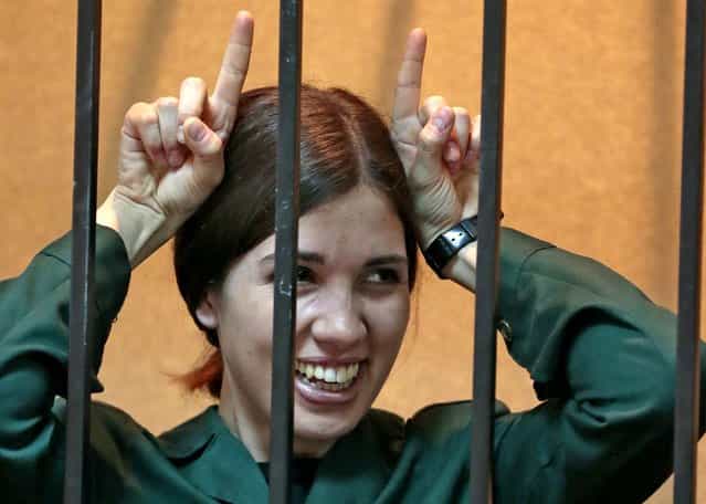 Nadezhda Tolokonnikova, a member of the feminist punk band Pussy Riot, gestures from behind bars at a district court in Zubova Polyana, on April 26, 2013. Tolokonnikova, in custody since her arrest in March 2012, is serving a two-year sentence for the band's irreverent protest against President Vladimir Putin in Moscow's main cathedral. A Russian court is to consider whether she is eligible for early release. (Photo by Mikhail Metzel/Associated Press)