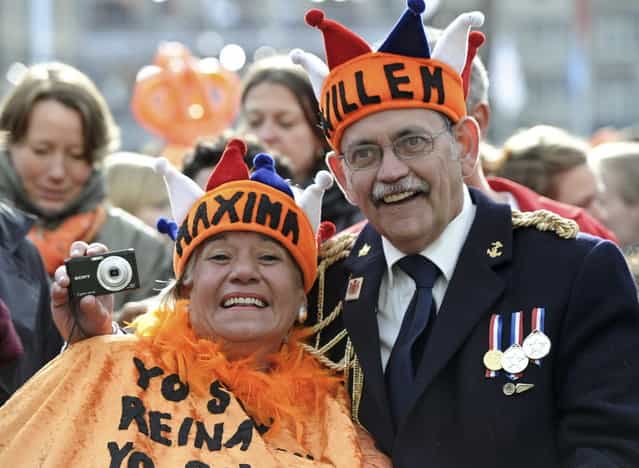 A couple waits for Queen Beatrix's abdication ceremony outside the Royal Palace in Amsterdam April 30, 2013. The Netherlands is celebrating Queen's Day on Tuesday, which will also mark the abdication of Queen Beatrix and the investiture of her eldest son Willem-Alexander. (Photo by Paul Vreeker/Reuters)