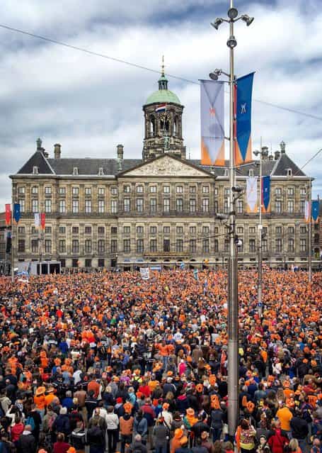 Peope, most of them wearing orange tee shirts, hats or plastic crowns, gather on April 30, 2013 at the Dam Square in Amsterdam, The Netherlands, to attend the investiture of the country's new King. Dutch Crown Prince Willem-Alexander became Europe's youngest monarch on Tuesday after his mother, Queen Beatrix, abdicated and his country hailed the avowedly 21st-century king with a massive, orange-hued party. (Photo by Koen van Weel/AFP Photo)