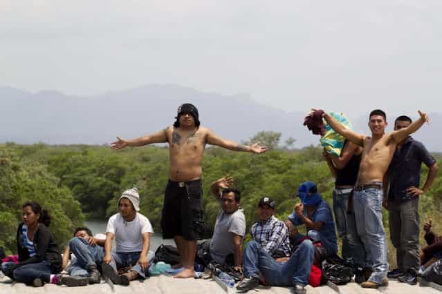 Migrants riding on top of a northern bound train toward the US-Mexico border acknowledge the photographer, in Union Hidalgo, southern Mexico, Monday, April 29, 2013. Migrants crossing Mexico to get to the U.S. have increasingly become targets of criminal gangs who kidnap them to obtain ransom money. (Photo by Eduardo Verdugo/AP Photo)