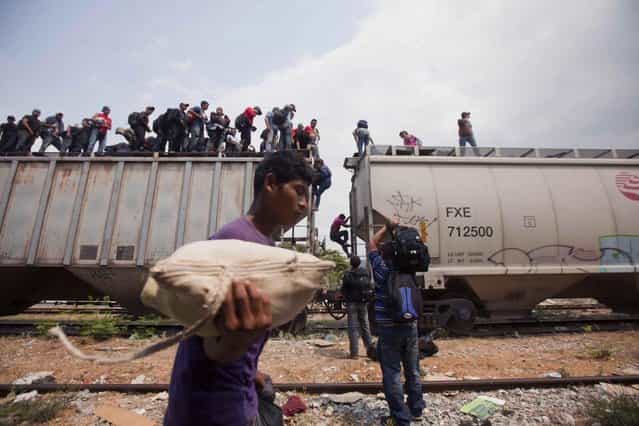 Migrants coming from Central America climb off a train during their journey toward the U.S.-Mexico border in Ixtepec, Mexico, Monday, April 29, 2013. Migrants crossing Mexico to get to the U.S. have increasingly become targets of criminal gangs who kidnap them to obtain ransom money. (Photo by Eduardo Verdugo/AP Photo)