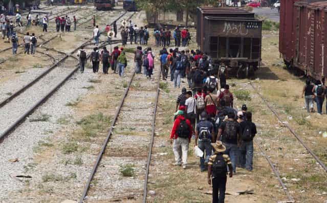 Migrants walk along the rail tracks after getting off a train during their journey toward the US-Mexico border in Ixtepec, southern Mexico, April 29, 2013. Migrants crossing Mexico to get to the U.S. have increasingly become targets of criminal gangs who kidnap them to obtain ransom money. (Photo by Eduardo Verdugo/AP Photo)