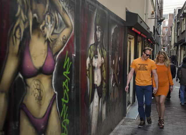 A man wearing a t-shirt which reads [Alexander is een fokking Koning] (Alexander is a fucking King) walks with his girlfriend in the red light district in Amsterdam April 28, 2013. The Netherlands is preparing for Queen's Day on April 30, which will also mark the abdication of Queen Beatrix and the investiture of her eldest son Willem-Alexander. (Photo by Cris Toala Olivares/Reuters)