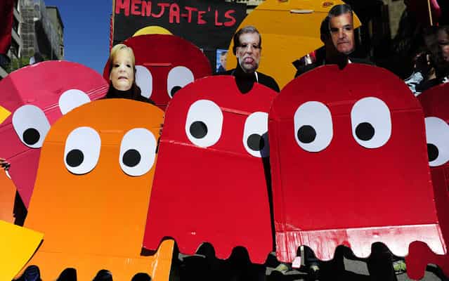 Demonstrators dressed up as characters of the video game Pac-Man and wearing masks of Spanish Prime Minister Mariano Rajoy (C) and German Chancellor Angela Merkel (L), take part a Labour Day march against the Spanish government's austerity policies in the centre of Barcelona on May 1, 2013. Tens of thousands protested across the globe for May Day to press for workers' rights amid tough economic times and to back an array of other causes. (Photo by Josep Lago/AFP Photo)
