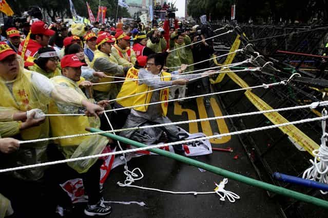 Workers try to pull a road block down during a protest on May Day in Taipei. More than 10,000 Taiwanese workers took to the streets to protest a government reform plan that will cut pension payouts to ease Taiwan's worsening fiscal problems. The protesters said the payout cuts reflect a longstanding government policy to bolster economic growth at the expense of workers' benefits and compromised workplace safety. (Photo by Chiang Ying-ying/Associated Press)
