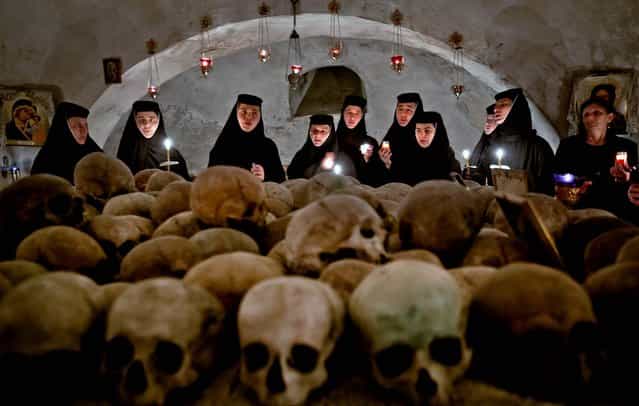 Orthodox nuns sing in the ossuary at the Pasarea monastery, outside Bucharest, Romania, during an Easter service, on May 5, 2013. The ossuary, containing mostly remains of nuns who lived at the monastery, is briefly opened on Easter night. (Photo by Vadim Ghirda/Associated Press)