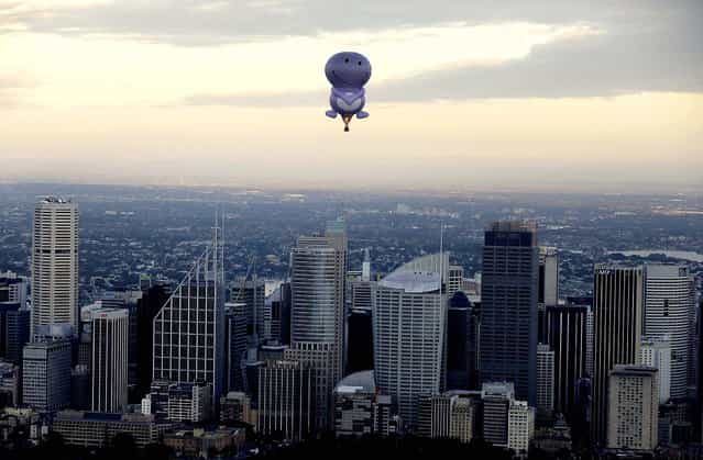 A hot air balloon from a fruit juice company called Nudie flies over Sydney Harbour and along the Sydney skyline, on May 6, 2013. (Photo by Rick Rycroft/Associated Press)
