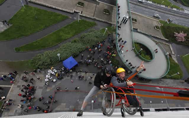 Jakub Koucky (R), a graduate from Jedlickuv Institute, is helped by a climber during the first ever attempt to rappel from Prague's Congress Center in a wheelchair, at an event to mark the institute's 100th founding anniversary in Prague, May 4, 2013. The institute was started by Rudolf Jedlicka a century ago to educate handicapped children. (Photo by Petr Josek/Reuters)