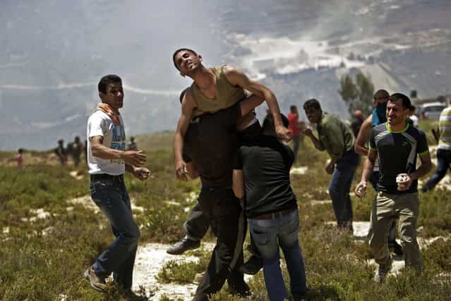 Palestinians help a wounded man during clashes with Jewish settlers near the Jewish settlement of Yitzhar, near Nablus, Tuesday, April 30, 2013. In the West Bank, a Palestinian man fatally stabbed an Israeli waiting at a bus stop and fired on police before he was detained by Israeli security forces, officials said. (Photo by Nasser Ishtayeh/AP Photo)