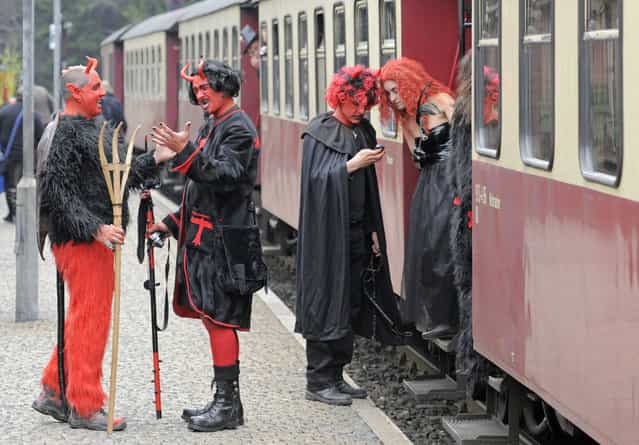 Men and women costumed as devils and witches stands besides a small train in Schierke, central Germany, Tuesday, April 30, 2013. Hundreds of costumed devils and witches meet to celebrate Walpurgis Night, a traditional religious holiday of pre-Christian origins. The event is named after St. Walburga, an English nun who helped convert the Germans to Christianity in the 8th century. (Photo by Jens Meyer/AP Photo)