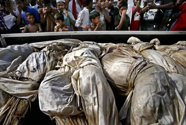 People cover their noses to block out the smell of decomposing bodies as a truck transporting unclaimed bodies from the garment factory building that collapsed, arrives for a mass burial, on May 1, 2013. The building collapse last week in the country's worst industrial disaster, killing at least 402 people and injuring 2,500. (Photo by Wong Maye-E/Associated Press)