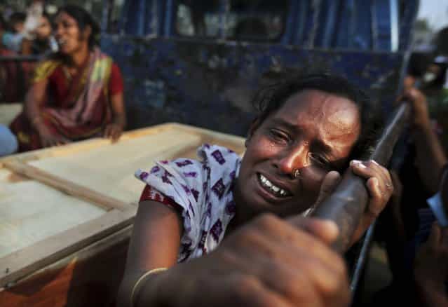A Bangladeshi woman weeps as she sits next to the coffin of a relative who died in a building that collapsed Wednesday in Savar, near Dhaka, Bangladesh, Sunday, April 28, 2013. A fire broke out late Sunday in the wreckage of the garment factory that collapsed last week in Bangladesh killing hundreds, with smoke pouring from the piles of shattered concrete and some of the rescue efforts forced to stop. (Photo by Kevin Frayer/AP Photo)