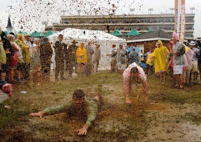 Fans slide through the mud in the infield prior to the 139th running of the Kentucky Derby at Churchill Downs, on May 4, 2013. (Photo by T. J. Root/Getty Images)