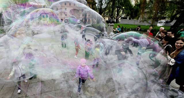 Children play with giant soap bubbles in downtown promenade of Krakowskie Przedmiescie in Warsaw, Poland, Saturday, May 4, 2013, one of many forms of entertainment offered to the residents during a long weekend of national holidays. (Photo by Czarek Sokolowski/AP Photo)