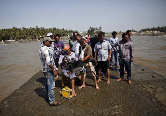 A cinematographer films, as other members of the crew watch, during the shooting of Bollywood film [Black Home] at a beach on the outskirts of Mumbai April 26, 2013. Indian cinema marks 100 years since Dhundiraj Govind Phalke's black-and-white silent film [Raja Harishchandra] (King Harishchandra) held audiences spellbound at its first public screening on May 3, 1913, in Mumbai. Indian cinema, with its subset of Bollywood for Hindi-language films, is now a billion-dollar industry that makes more than a thousand films a year in several languages. It is worth 112.4 billion rupees (over $2 billion) and leads the world in terms of films produced and tickets sold. (Photo by Danish Siddiqui/Reuters)