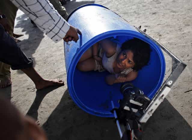 Bollywood actress Chitrashi Rawat lies in a plastic drum as she is briefed by a crew member during the shoot for the film [Black Home] at a beach on the outskirts of Mumbai April 26, 2013. (Photo by Danish Siddiqui/Reuters)