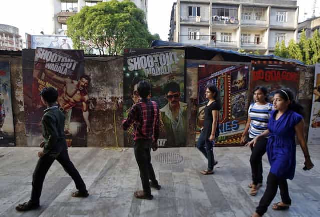 People walk past Bollywood film posters in Mumbai April 14, 2013. (Photo by Danish Siddiqui/Reuters)