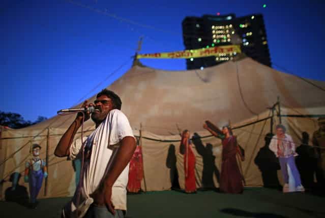 An employee of Anoop Touring Talkies, a travelling tent cinema company, speaks into a microphone to advertise a film in Mumbai April 23, 2013. (Photo by Danish Siddiqui/Reuters)