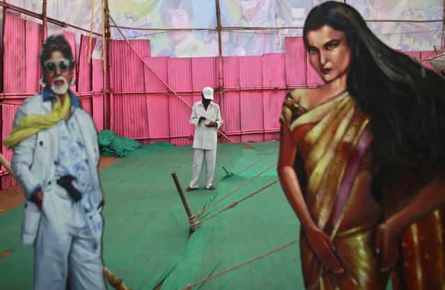 An employee of Anoop Touring Talkies, a travelling tent cinema company, stands between cut-outs of Bollywood actors Amitabh Bachchan and Rekha in Mumbai April 23, 2013. (Photo by Danish Siddiqui/Reuters)