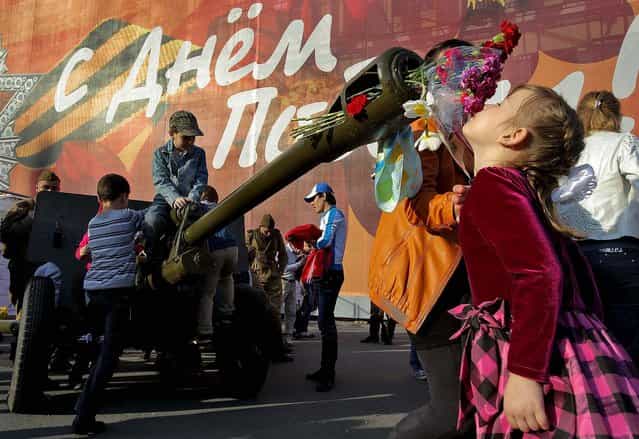 A girl smells the flowers inserted in the barrel of an artillery canon during Victory Day celebrations in St. Petersburg, Russia. (Photo by Dmitry Lovetsky/Associated Press)